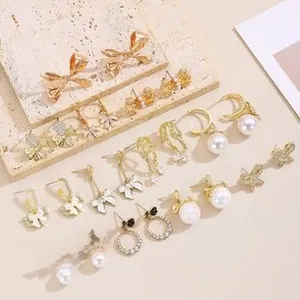 Close-up of golden bow earrings set featuring pearls and rhinestones on stone background
