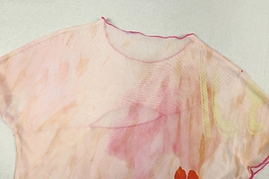 Détail du haut en maille transparente avec imprimé aquarelle montrant le col rond et l'ourlet