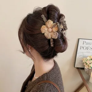 Knitted flower hair claw clip for women in brown fabric on a stylish bun hairstyle