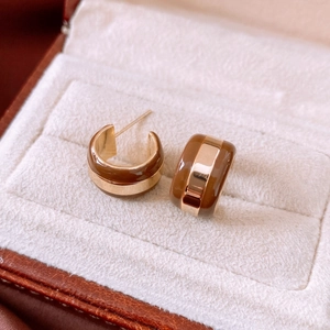 Macro view of gold-plated striped C-shaped stud earrings in a white velvet jewelry box