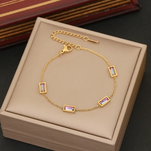 Detail of gold bracelet featuring rectangular purple crystals and lobster clasp closure