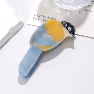 Macro detail of bird-shaped acetate hair claw clip with colorful marble feather pattern