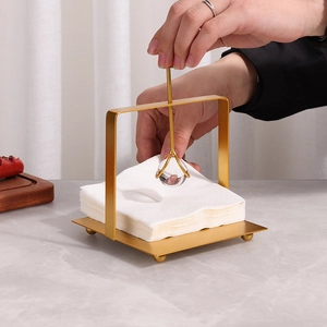Modern gold square napkin holder with crystal ball gravity arm on marble tabletop