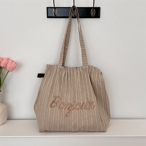 Close-up of Bonjour embroidery on a striped canvas tote bag with drawstring detail