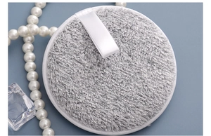 Detail of round gray bamboo charcoal fiber makeup remover pad with white ribbon loop