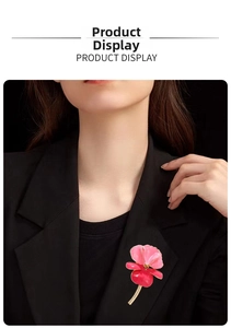 Detail of red enamel iris brooch pinned on black suit lapel for an elegant formal look