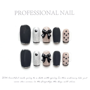 Macro detail of handmade press-on nails featuring black matte texture and 3D bow accents