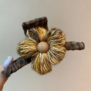 Macro view of handmade knit flower hair claw with wool texture and bead detail