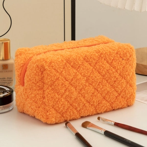 Close-up of orange sherpa storage bag with quilted pattern and gold zipper detail