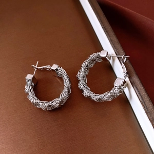 Detail showing high-polish woven texture of silver-plated hoop earrings with intricate metal spiral
