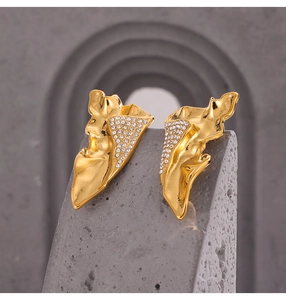 Macro shot of gold-plated titanium earrings with wing textures and sparkling diamonds