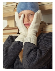 Close-up of soft white knitted wool gloves worn by a model in a warm cozy setting