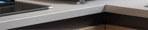 Detailed view of smooth light gray quartz kitchen countertop corner with seamless cabinet joints