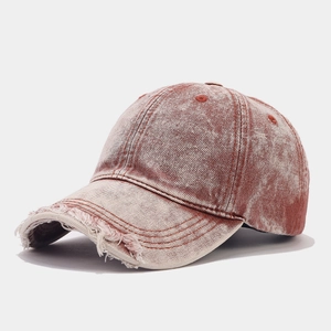 Detail view of red-brown washed denim baseball cap with distressed frayed edges