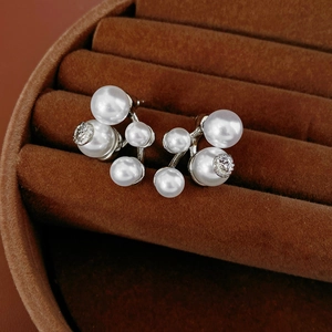 Macro shot of pearl cluster earrings with embossed metal detail in a velvet box
