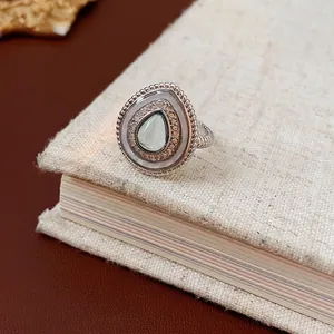 Bague goutte vintage avec pierre bleu clair et zircons posée sur le bord d'un livre