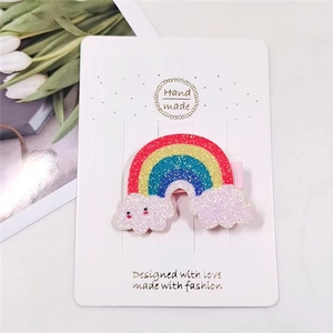 Close-up of glitter rainbow hair clip with clouds on pink fabric alligator clip detail