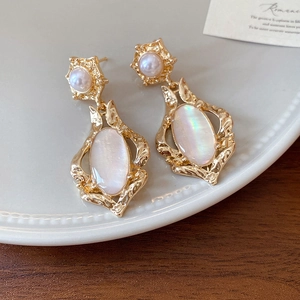 Detail view of 18k gold plated tiger eye earrings with pearls on a ceramic tray