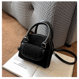 Detail view of the black plush patchwork handbag with zipper and rigid handle