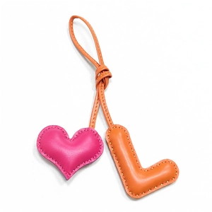Handmade leather bag charm featuring a pink heart and orange letter L with stitch detail