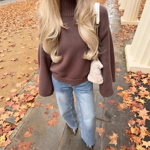 Maglione a dolcevita marrone scuro da donna in maglia spessa su foglie autunnali