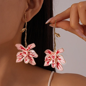 Detailed close-up of pink flower earrings with red texture on professional model