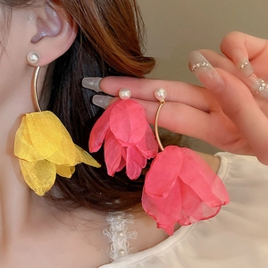 Detail view of large lace tulip petal earrings with faux pearl on model