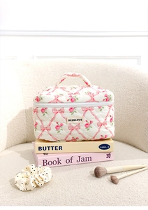 Quilted floral makeup bag with pink bow and ribbon, professional layout on books