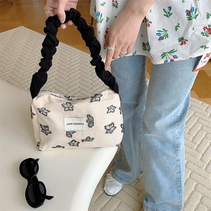 Detail of cream canvas tote featuring butterfly print and black ruffled handle design