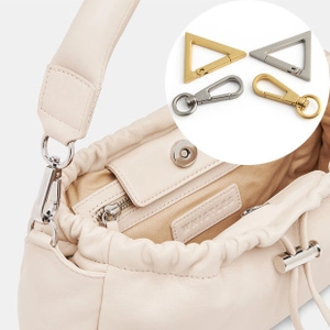 Detail of cream faux leather mini bag with drawstring closure and metal hook attachments