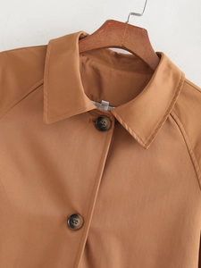 Close-up of camel trench coat featuring classic lapels and dark brown resin buttons