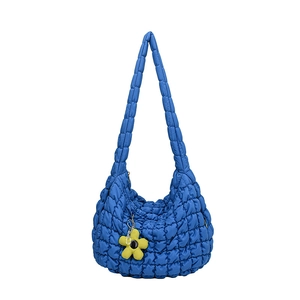 Blue quilted puff tote bag with a yellow flower charm on a clean white background