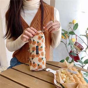 Close-up of corduroy pencil case with orange floral patterns and round metal zipper
