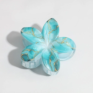 Detail of blue marble lily hair claw clip with golden veins and resin petal texture