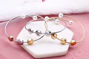 Three-tone stainless steel wire bracelets with pearls on a marble display tray