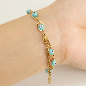 Gros plan d'un bracelet œil porte-bonheur doré avec breloque bleue au poignet féminin