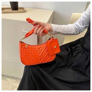 Detail of orange quilted crescent bag with scrunched cloud handle and mini pouch