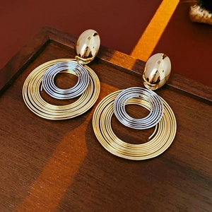 Macro shot of gold and silver coiled metal earrings on a dark brown wooden tray
