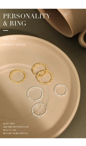 Detail of minimalist hammered gold and silver stacking rings on a ceramic tray