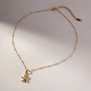 Detailed close-up of K18 hallmark stamp on gold starfish pendant necklace extension chain