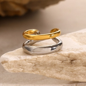 Detail of minimalist two-tone intertwined gold and silver ring on natural raw stone