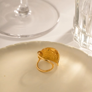 Gold irregular textured open ring with hammered finish on a minimalist ceramic plate