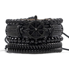 Detail of multi-layer black leather bracelet set featuring a metallic ship wheel charm