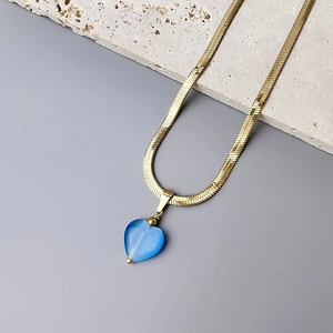 Detail of 18K gold snake chain necklace with a deep blue heart-shaped cat eye stone pendant
