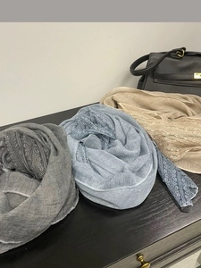 Detailed view of gray blue and beige linen scarves with delicate lace trim accents