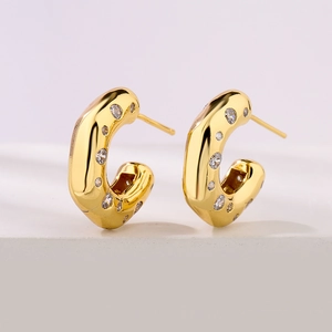 Pair of gold C-shaped earrings with clear zircon stones on a white background
