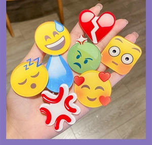 Dettaglio di simpatici fermagli per capelli emoji in acrilico con varie espressioni