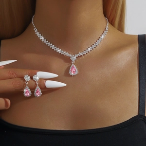Gros plan d'une parure de bijoux avec cristal rose en goutte, collier et boucles d'oreilles