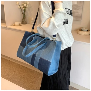 Detail view of denim patchwork tote bag with multi-tone blue layers and golden hardware