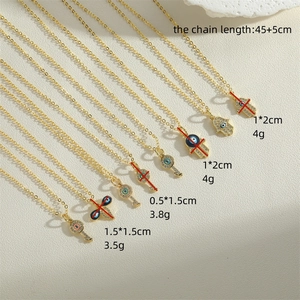 Bohemian gold necklaces with Hamsa hand and Evil Eye enamel pendants on sandstone